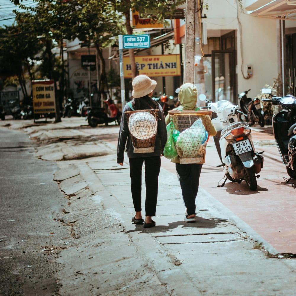 Passants en chapeaux coniques dans une rue commerçante du Vietnam